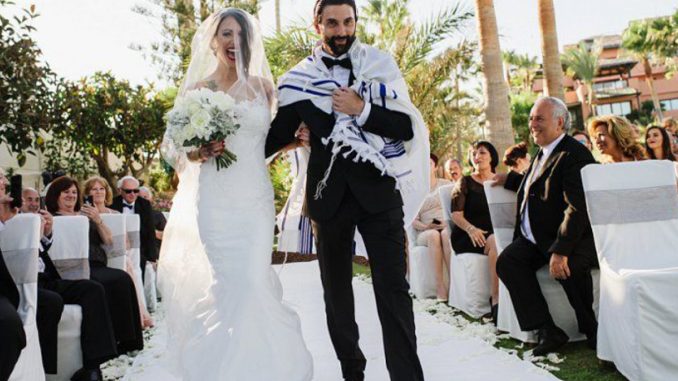 Picture Featuring Happy Sming Bride & Groom Entering To The Stage In Their Grand Wedding Ceremony In A Restaurant.