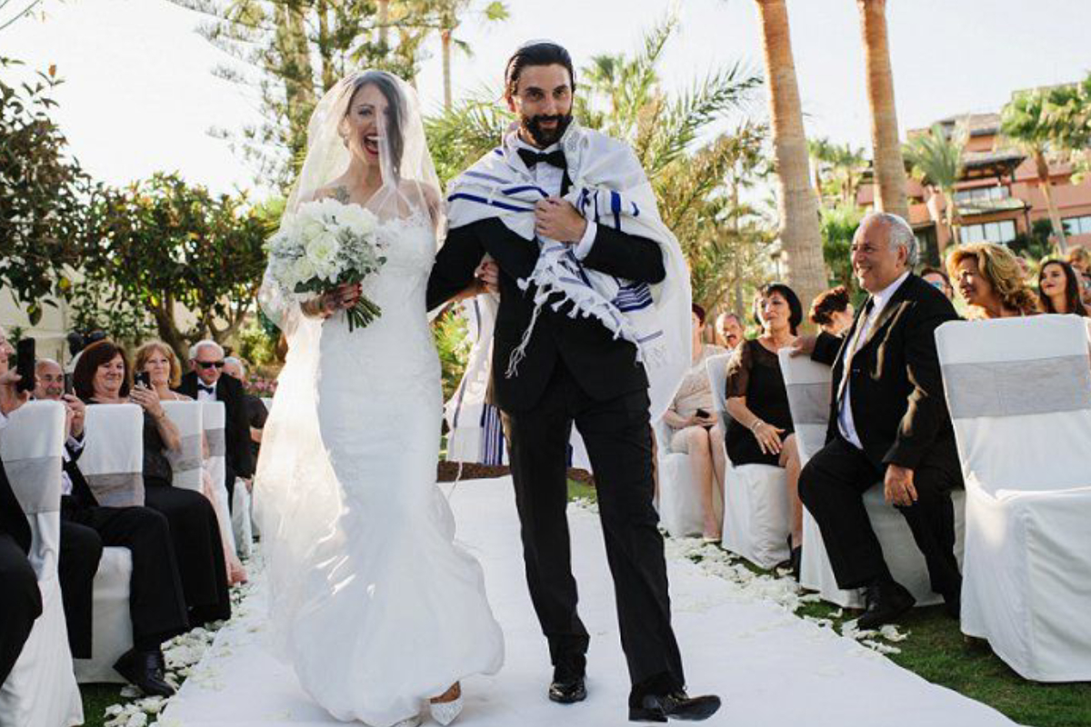 Picture Featuring Happy Sming Bride & Groom Entering To The Stage In Their Grand Wedding Ceremony In A Restaurant.