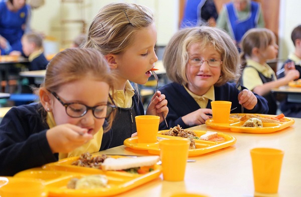 Three girls are having lunch in school cafe.